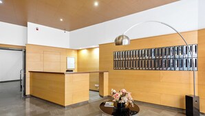 A reception area with a wooden reception desk, a wall-mounted mail rack, a round table with a vase of flowers, and a tall floor lamp. - Stay U-nique Apartment Sebastián Souvirón (Málaga)