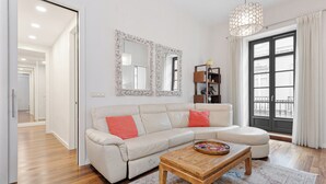 A modern living room with a beige sofa, a wooden coffee table, and a large window with curtains. - Stay U-nique Apartment Sebastián Souvirón (Málaga)