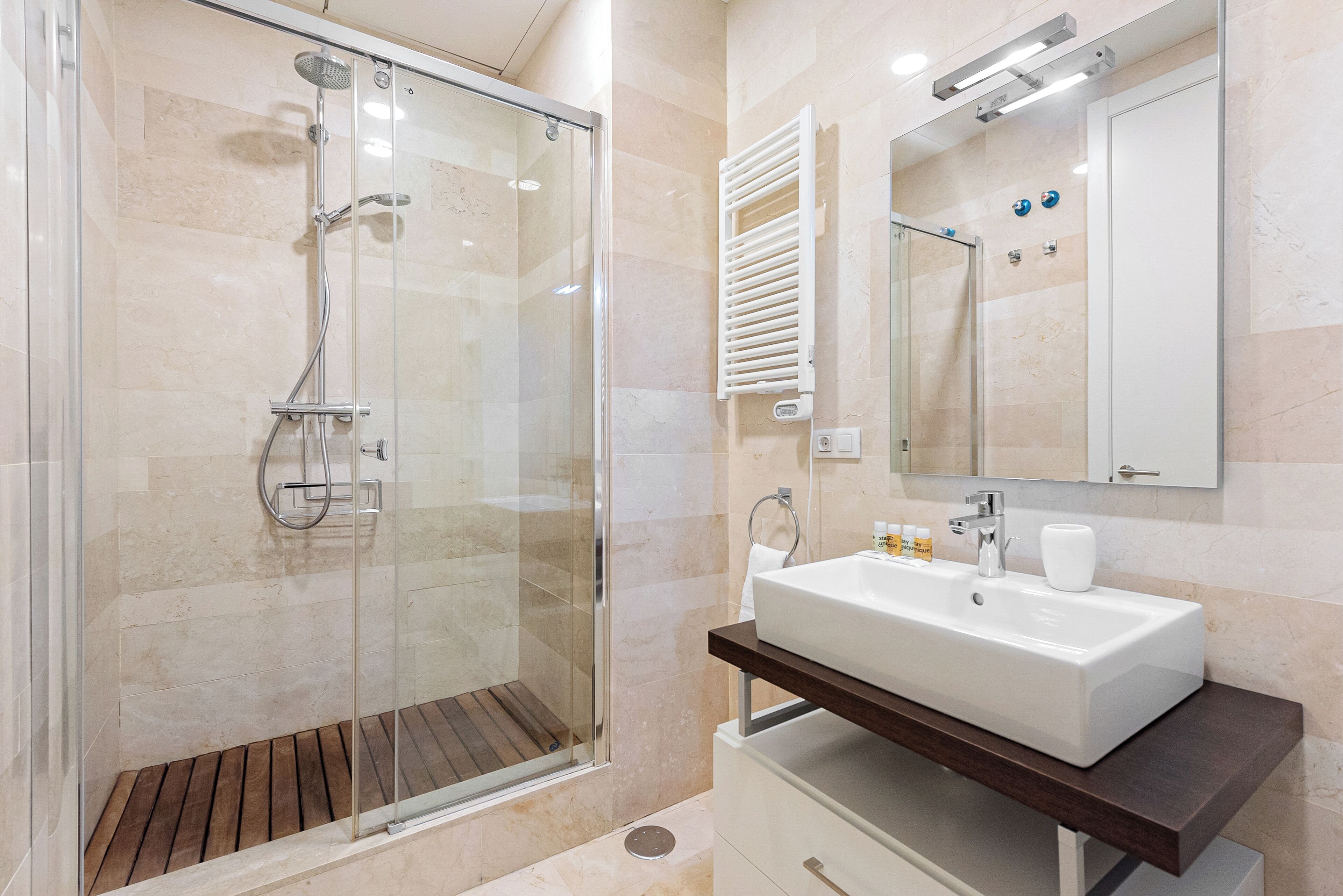 A modern bathroom with a glass-enclosed shower, a white sink, and a mirror above it.