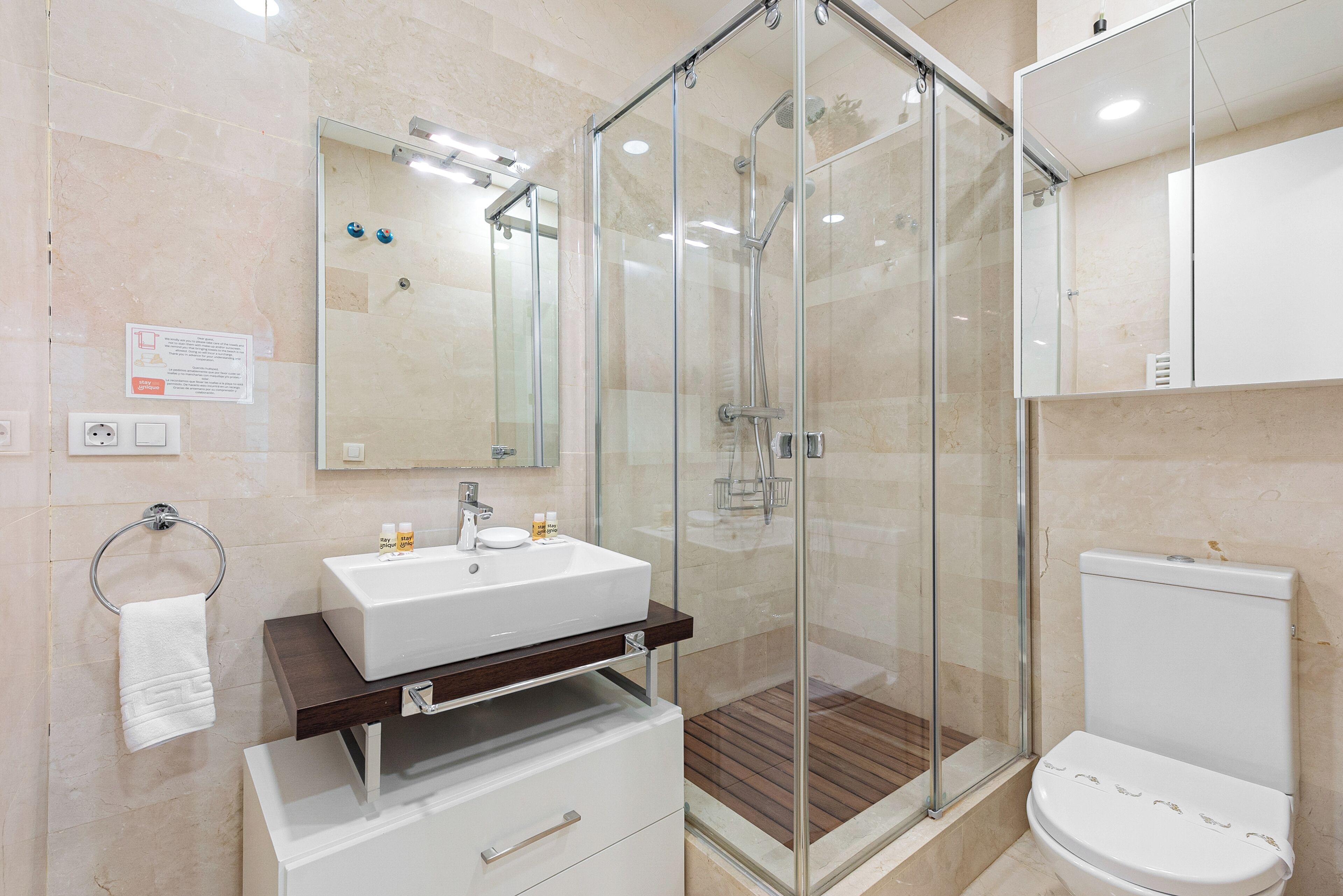 A modern bathroom with a glass-enclosed shower, a white sink, and a toilet.