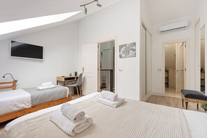 Ein Hotelzimmer mit zwei Betten, einem Schreibtisch, einem Stuhl, einem Fernseher und einem durch eine offene Tür einsehbaren Badezimmer.