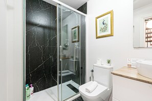 Ein modernes Badezimmer mit einer Glaskabine zur Dusche, einer Toilette und einem Waschbecken.