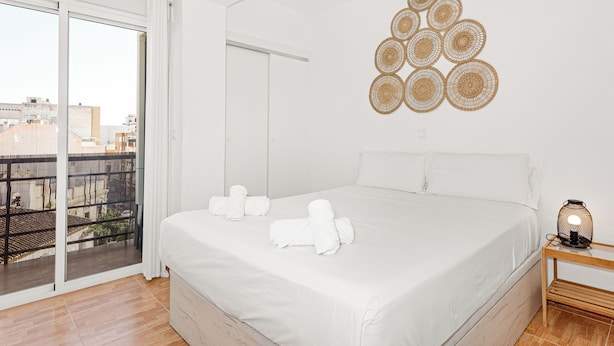 Een slaapkamer met een groot bed, een balkon met uitzicht en een wanddecoratie.