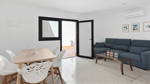 A modern living room with a dining area, a sofa, and a coffee table. - Stay U-nique House Reina Juliana (Málaga)