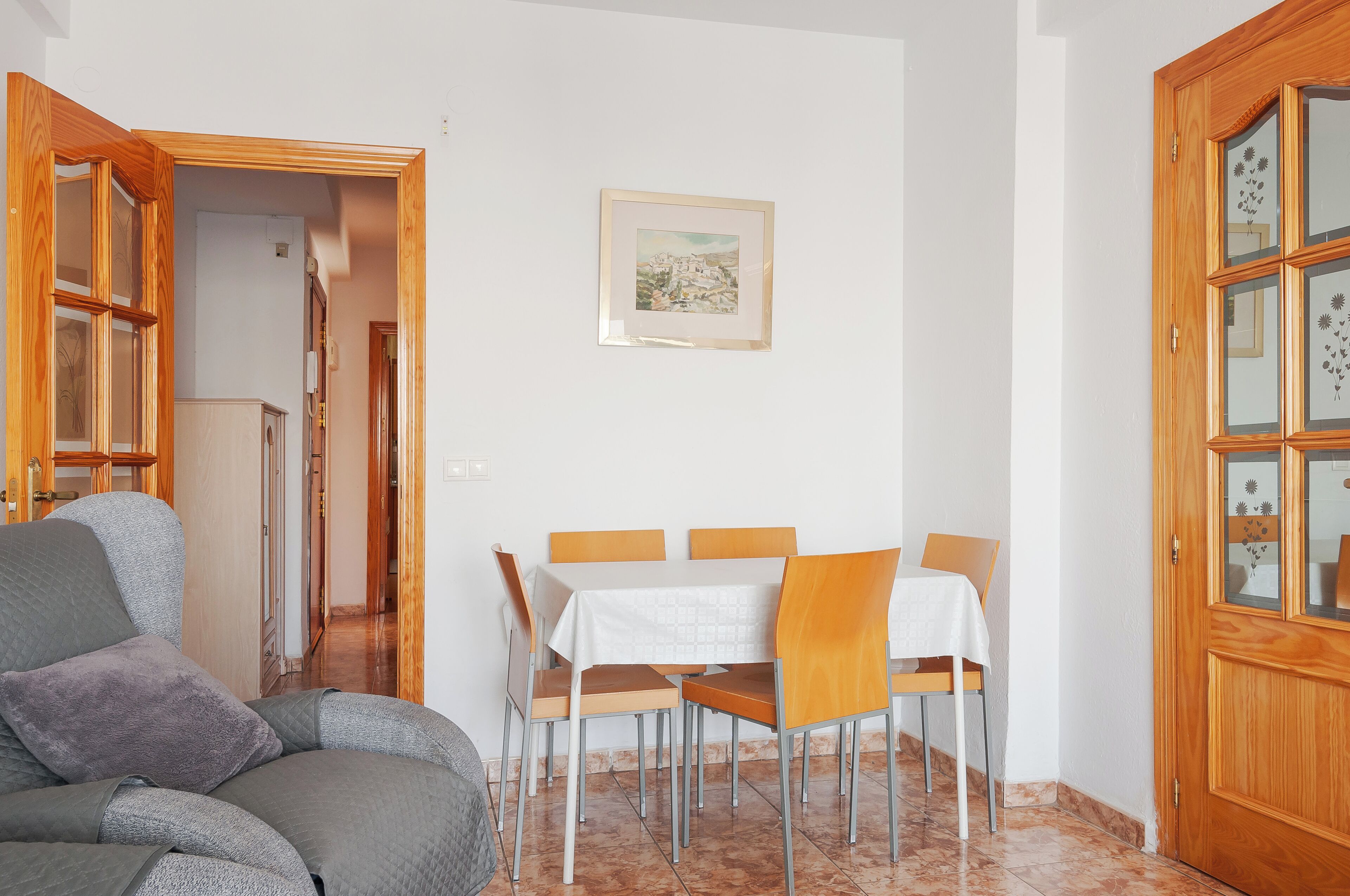 A dining area with a table set for four, surrounded by wooden chairs.