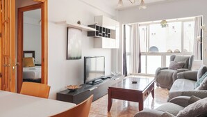Un salon moderne avec un téléviseur, un canapé et un coin repas.