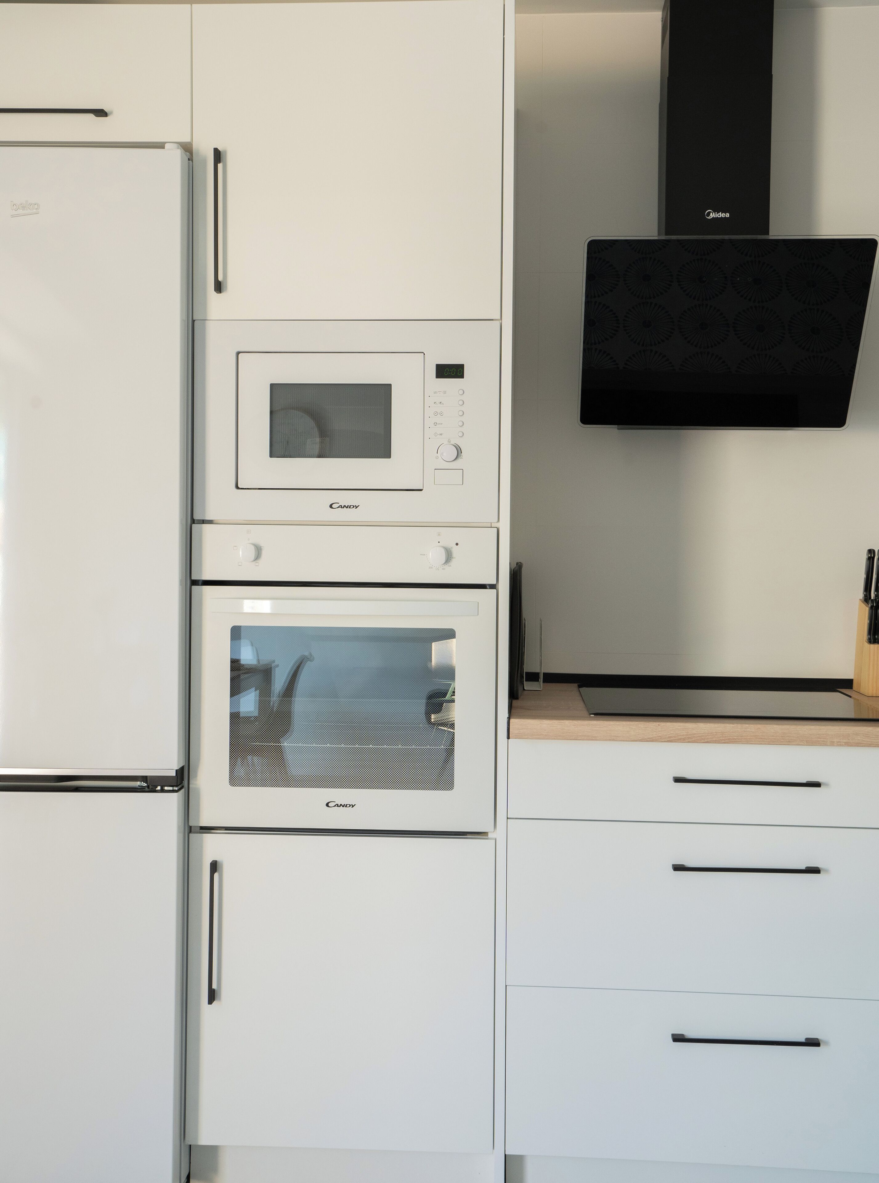 A kitchen with a built-in microwave, oven, and a flat-screen TV mounted above the counter.