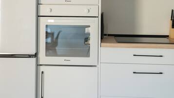 A kitchen with a built-in microwave, oven, and a flat-screen TV mounted above the counter.