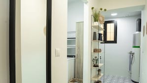Ein Korridor mit einem gemusterten Boden, einem Spiegel, einem Regal mit Dekoration und einem Kühlschrank.