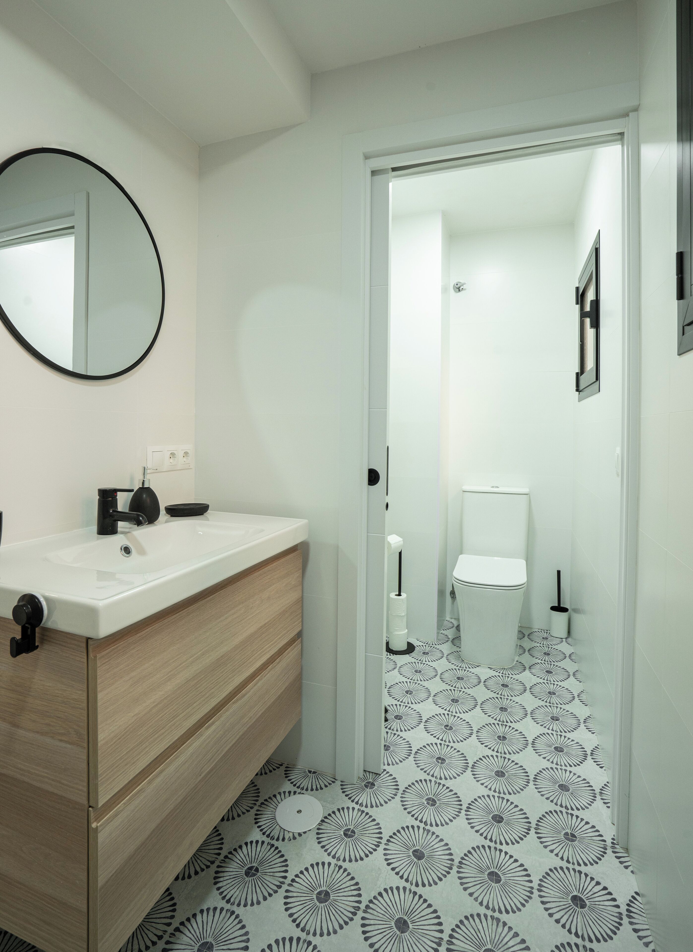 Un baño moderno con un lavabo blanco, espejo e inodoro.