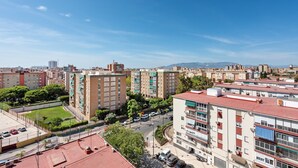 Un immeuble résidentiel à plusieurs étages, doté de balcons, d’un espace de stationnement et offrant une vue dégagée sur le paysage urbain environnant.