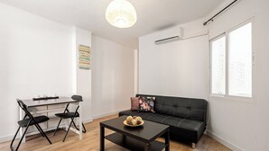 A modern living space with a black sofa, a dining table with chairs, and a coffee table.