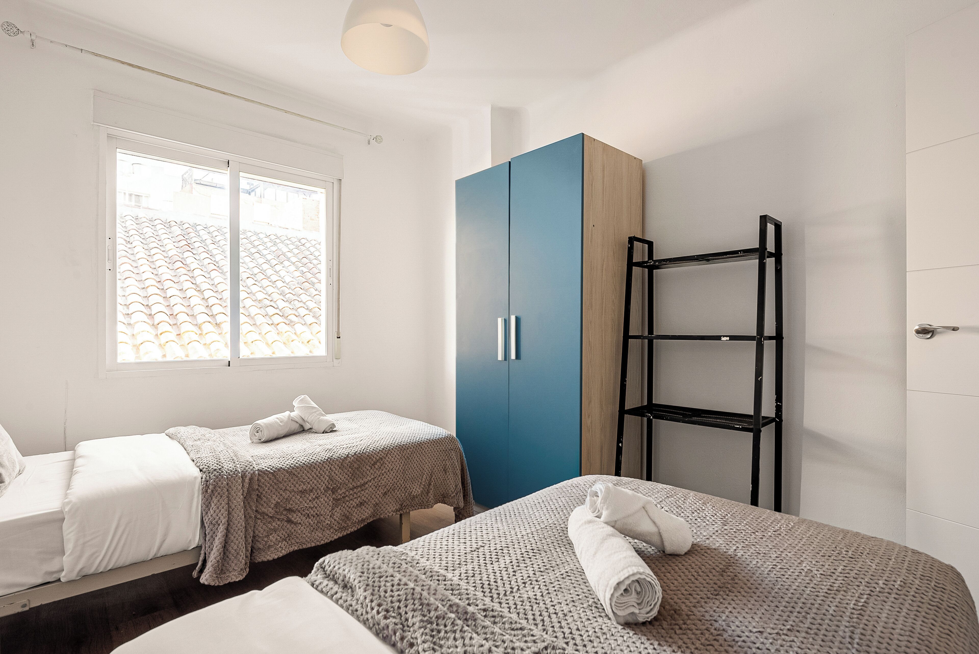 Une chambre avec deux lits, une armoire et une étagère.
