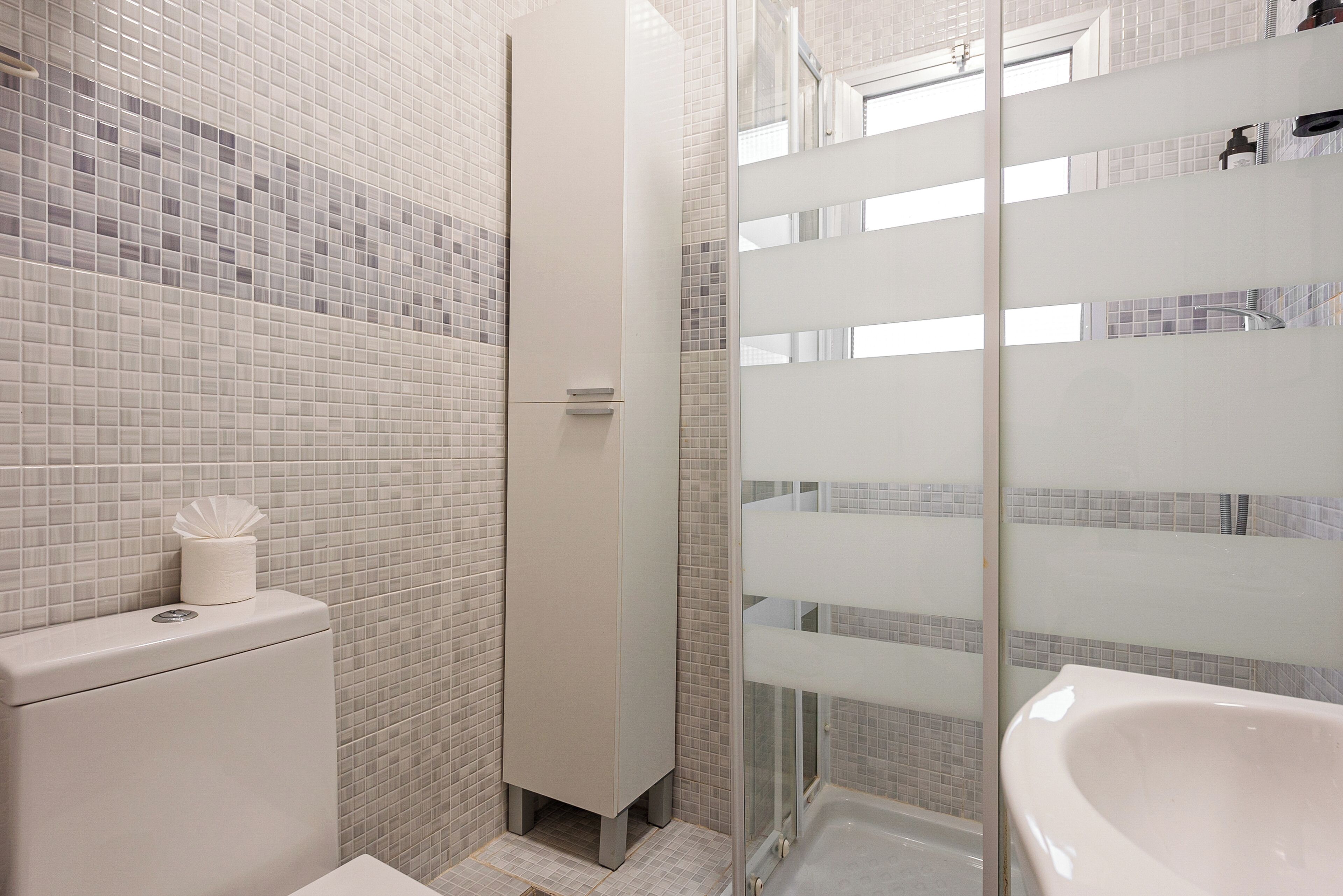 A bathroom with a toilet, a cabinet, and a bathtub.