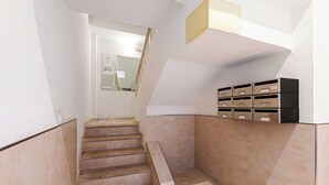 A staircase with a handrail, a set of mailboxes, and a door leading to another room.