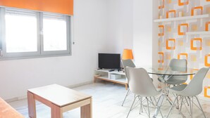 Ein modernes Wohnzimmer mit Fernseher, Glastisch und Sesseln.