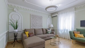 Una sala de estar con un sofá, un sillón verde, una mesita y una planta en maceta.