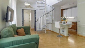 Un apartamento moderno con un sofá verde, una cocina con encimera blanca y una escalera en espiral.