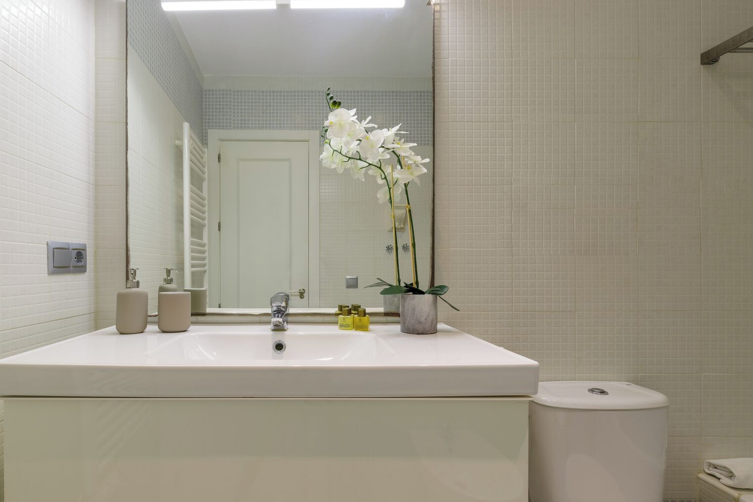 Een badkamer met een wit wastafel, spiegel, toilet en een potorkidee.