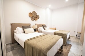 A hotel room with two beds, a woven wall decoration, and a small table. - Stay U-nique Apartments Plaza Constitución (Málaga)
