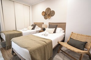 A hotel room with two beds, a wicker chair, and a wall-mounted decorative piece. - Stay U-nique Apartments Plaza Constitución (Málaga)