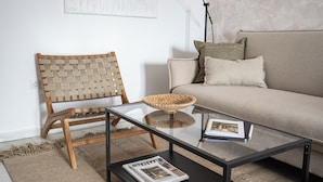 A modern living room with a glass coffee table, a woven chair, and a beige sofa. - Stay U-nique Apartments Plaza Constitución (Málaga)