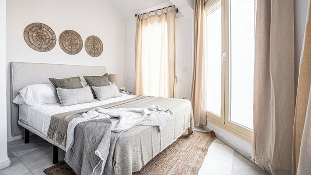 A bedroom with a bed, pillows, a bedside table, and a window with curtains. - Stay U-nique Apartments Plaza Constitución (Málaga)