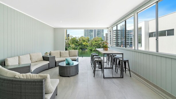 A modern balcony with a sofa, dining table, and chairs.