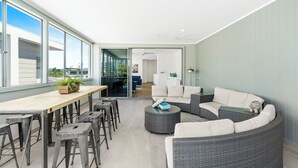 A modern living room with a dining area, large windows, and a view of the city.