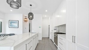 A modern kitchen with white cabinetry, a marble countertop, and stainless steel appliances.