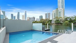 A rooftop pool with a city skyline view, a dock, and a water body.