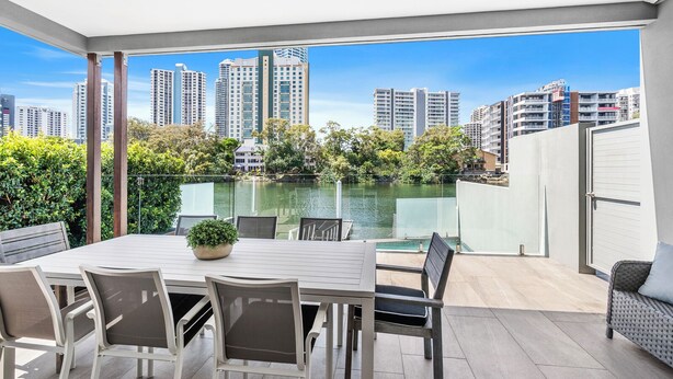 A modern outdoor dining area with a view of a city skyline and a body of water.