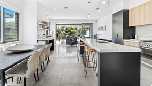 A modern kitchen with a large island, bar stools, and a dining area with a round table and chairs.