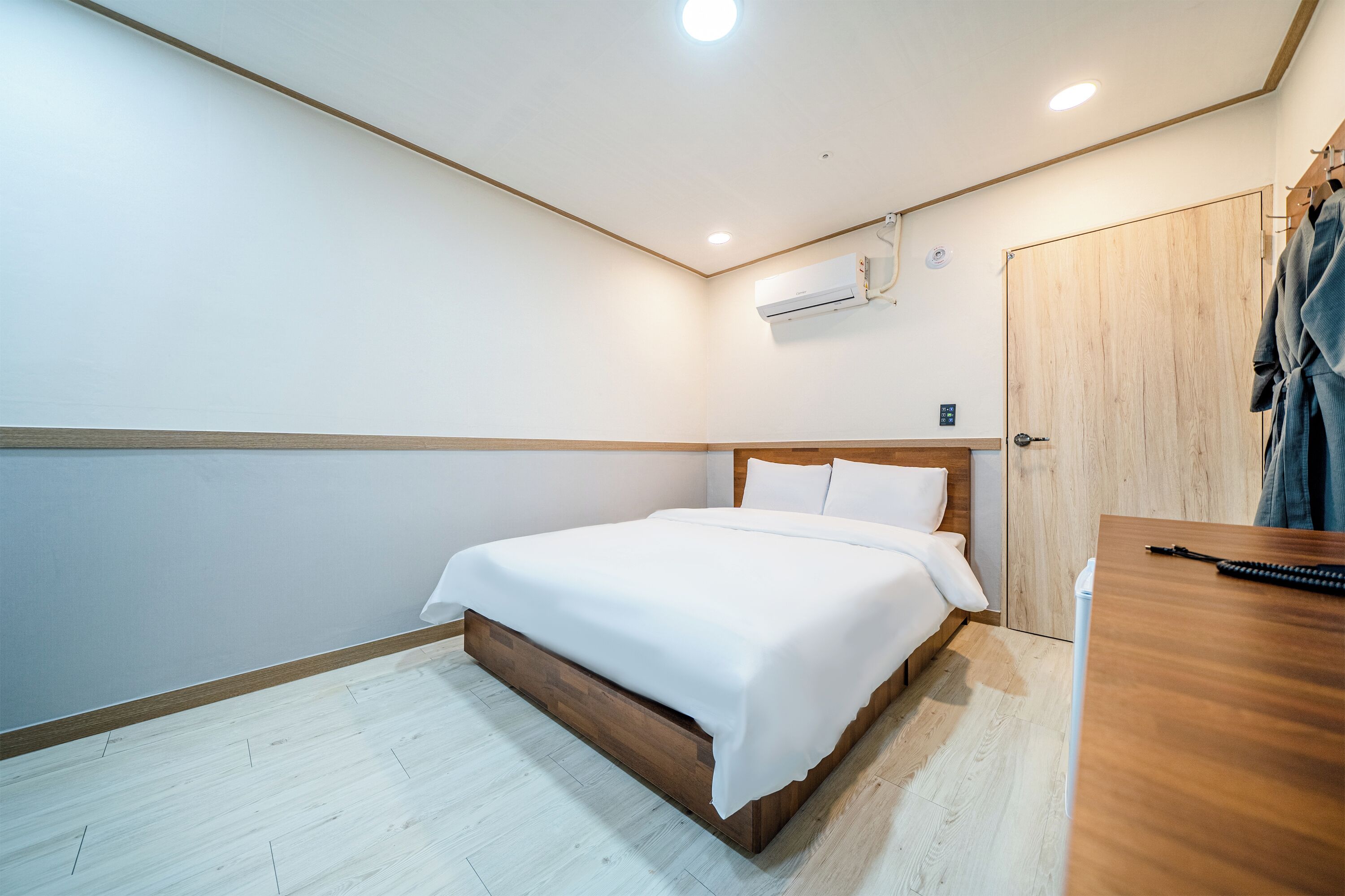A neatly arranged bedroom with a wooden bed, a wooden desk, and a wardrobe.
