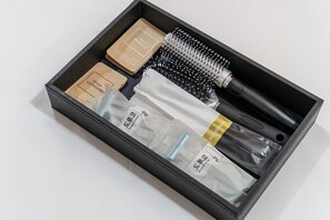 Une trousse de toilette noire contenant un savon moussant, une brosse et plusieurs petits flacons.