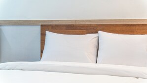 Ein Bett mit weißer Bettwäsche und einem Holzkopfende.