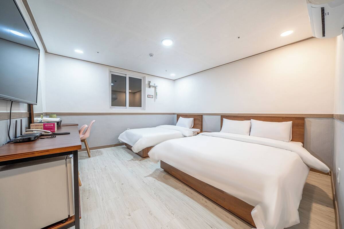 Ein Hotelzimmer mit einem Holzbett, einem Schreibtisch mit Stuhl, einem Fernseher und einem Fenster.