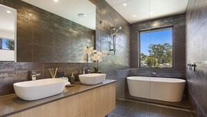 Un baño moderno con dos lavamanos, una bañera y un espejo grande.