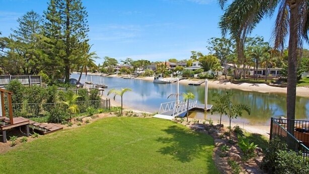 Un barrio residencial con un lago, un muelle y un césped bien cuidado.
