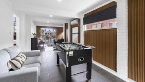 Een moderne binnenruimte met een tafelvoetbaltafel, een bank en een eethoek.