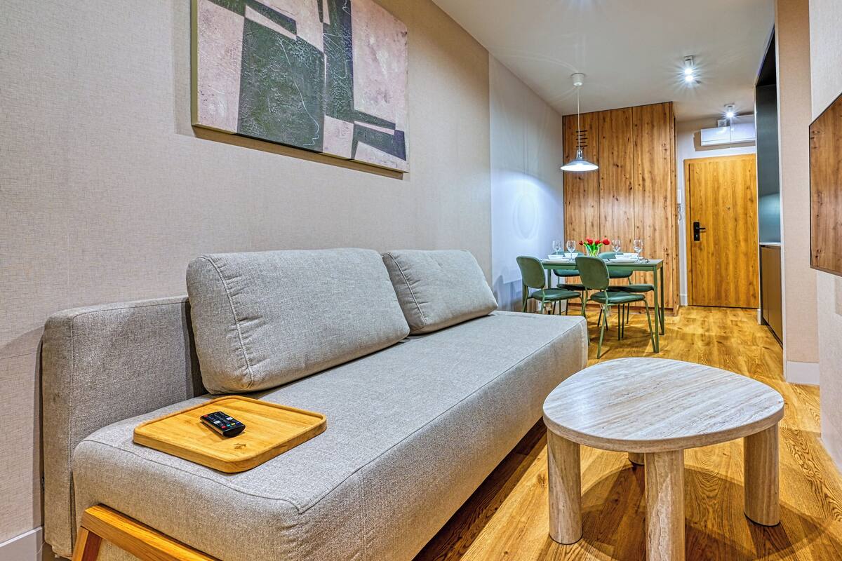 Ein modernes Wohnzimmer mit einem grauen Sofa, einem Holztablett und einem runden Tisch.