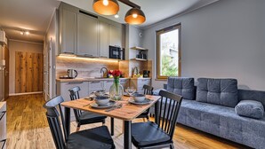 Une cuisine moderne avec des meubles de couleur grise, une table à manger en bois et un canapé gris.