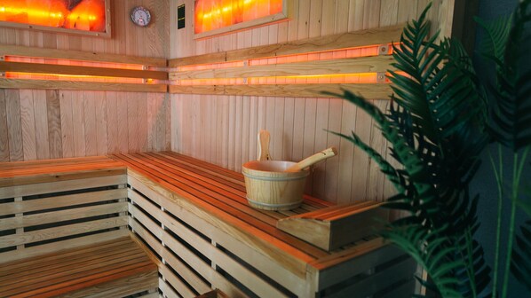 Una sauna con bancos de madera, un balde de madera y un calentador fijado a la pared.