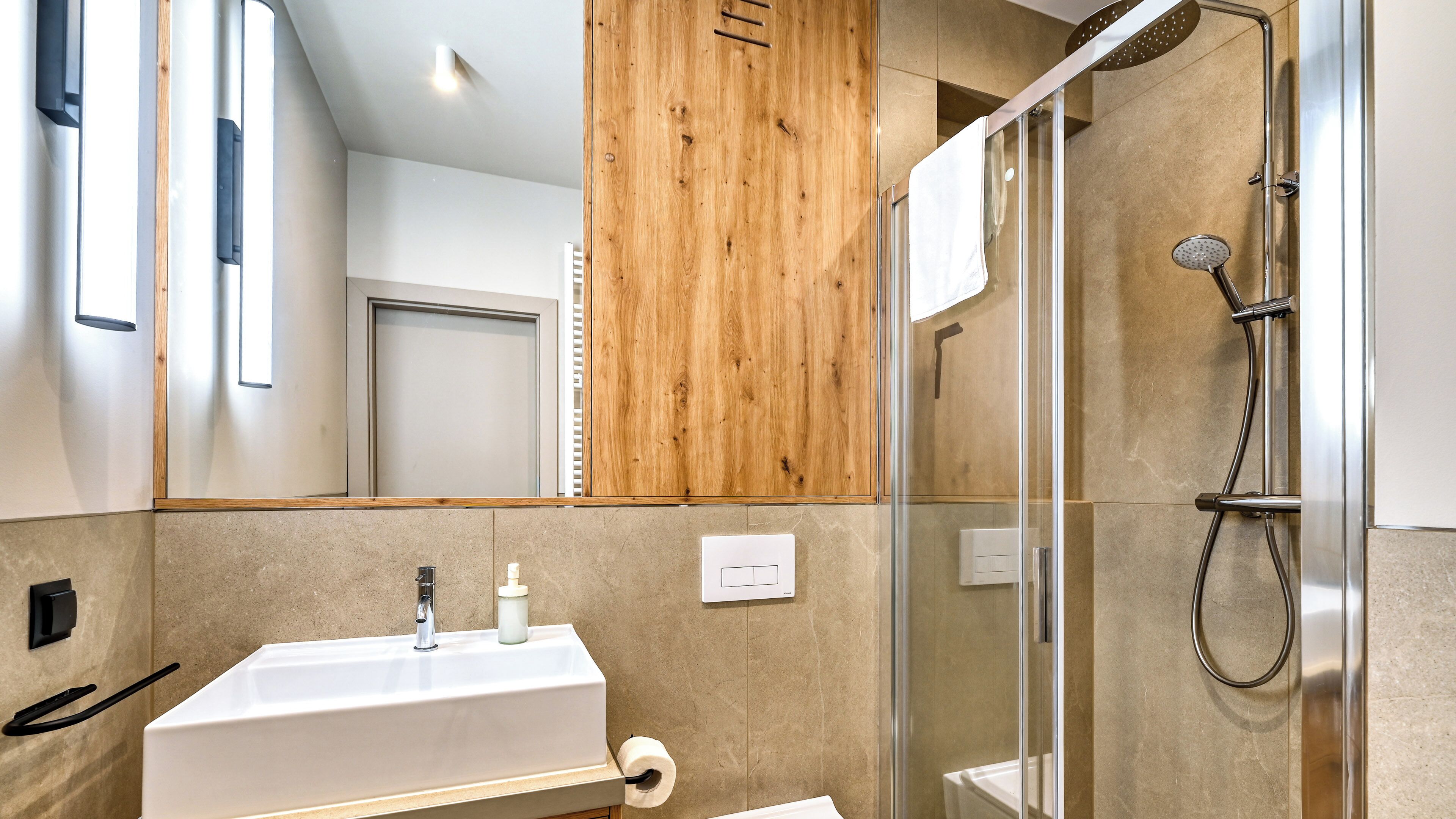 A modern bathroom with a glass shower enclosure, a white sink, and a wooden panel wall.