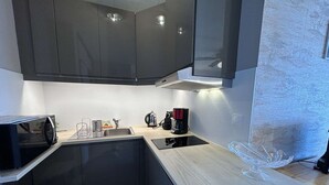 A modern kitchen with dark cabinets, a microwave, a coffee maker, and a sink. - Sea view studio in Saint Jean de Monts, parking included (Saint-Jean-de-Monts)