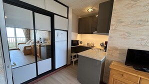 A compact kitchen with a refrigerator, microwave, and coffee maker. - Sea view studio in Saint Jean de Monts, parking included (Saint-Jean-de-Monts)