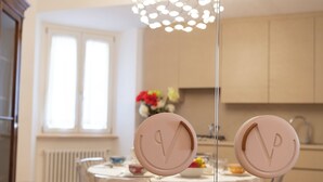 Une cuisine moderne avec une table de salle à manger ronde, un luminaire blanc au plafond et une fenêtre avec des stores.