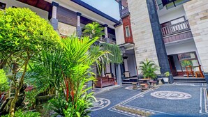 A courtyard with a pool, potted plants, and a wooden bench.