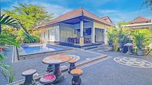 A house with a swimming pool, outdoor seating, and potted plants.