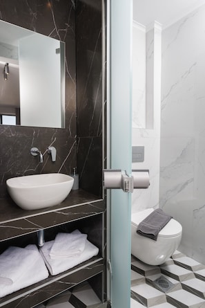 Et moderne badeværelse med en marmorvask, toilet og håndklædestang.